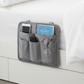 Bedside caddy hanging organizer with pockets holding phone, book and remote on side of bed