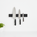 Magnetic knife strip wall mount in black wood holding kitchen knives on wall
