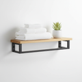 Wall-mounted matte black towel bar with wooden shelf holding towels and small plant